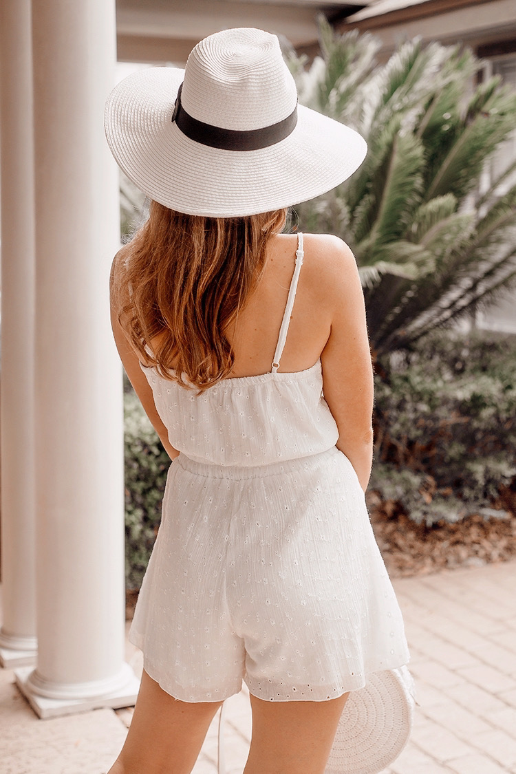 white romper, wide brimmed panama hat, white straw bag